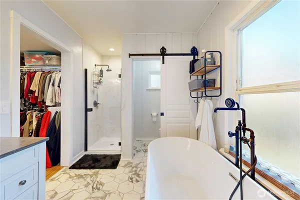 a walk in closet with wooden floor and a rug