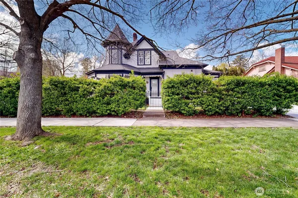 a view of a brick house with large windows and a yard with plants