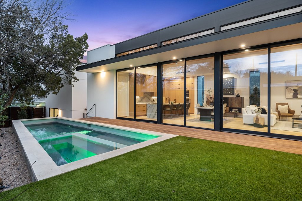 910 West Johanna Street Austin, TX 78704 - Photo 29 of 37 Back of house at dusk featuring a lawn, a pool with connected hot tub, and a patio