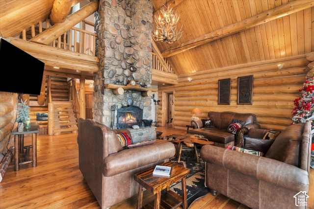 1701 Oak Road Coalville, UT 84017 - Photo 16 of 71 Living area featuring a stone-clad fireplace, log walls, wood-finish flooring, a vaulted wood-paneled ceiling, and a built-in staircase