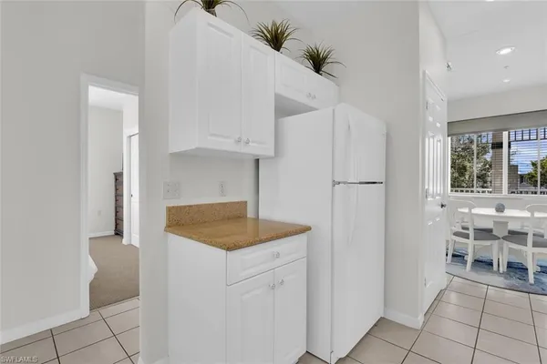 a kitchen with white cabinets and window