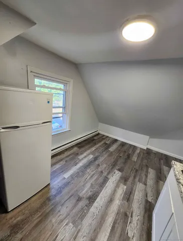 a view of a room with wooden floor and a refrigerator