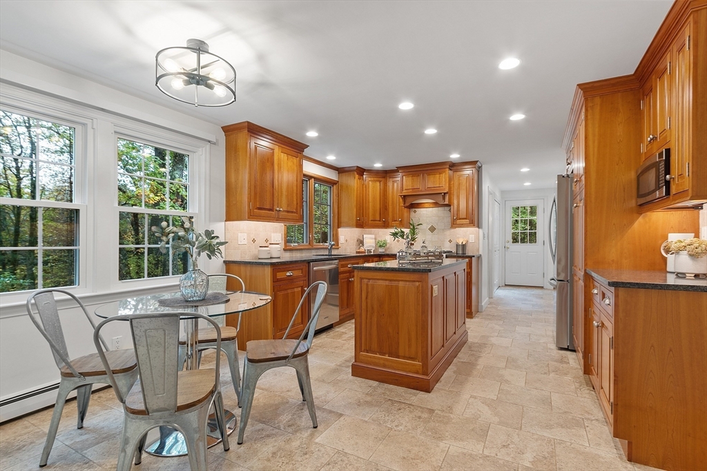 31 Herrick Road Boxford, MA 01921 - Photo 7 of 40 a kitchen with stainless steel appliances granite countertop a stove a refrigerator a oven a sink a dining table and chairs with wooden floor