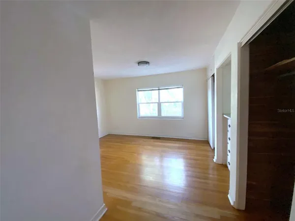 a view of hallway with window and wooden floor