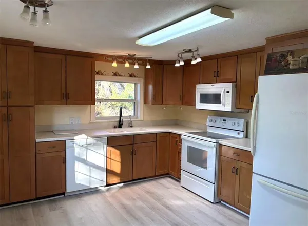 a kitchen with stainless steel appliances granite countertop a sink dishwasher a refrigerator and a stove with wooden floor