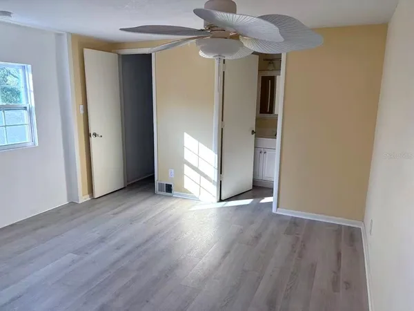 an empty room with wooden floor closet and windows