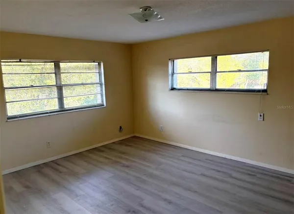 an empty room with wooden floor and windows