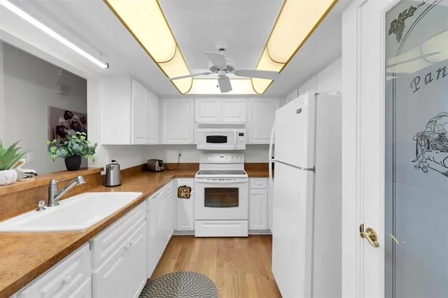 a kitchen with stainless steel appliances white cabinets and wooden floor