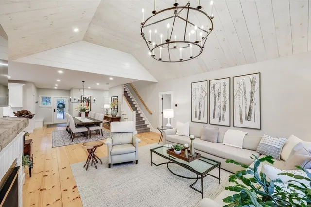 a view of a dining room and livingroom with furniture wooden floor a chandelier
