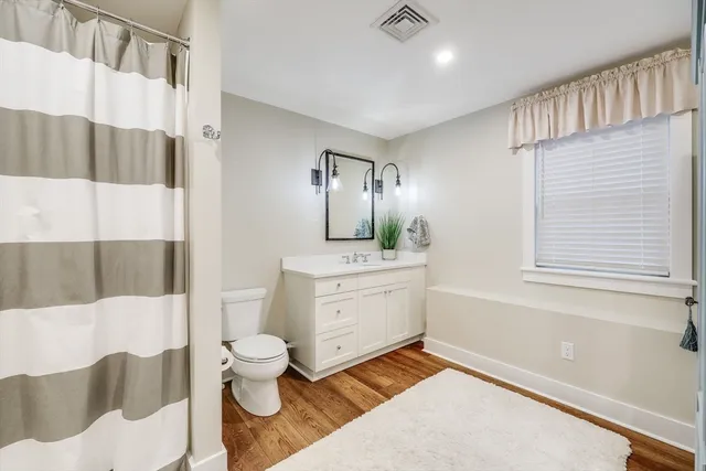 a bathroom with a toilet sink a mirror and a shower