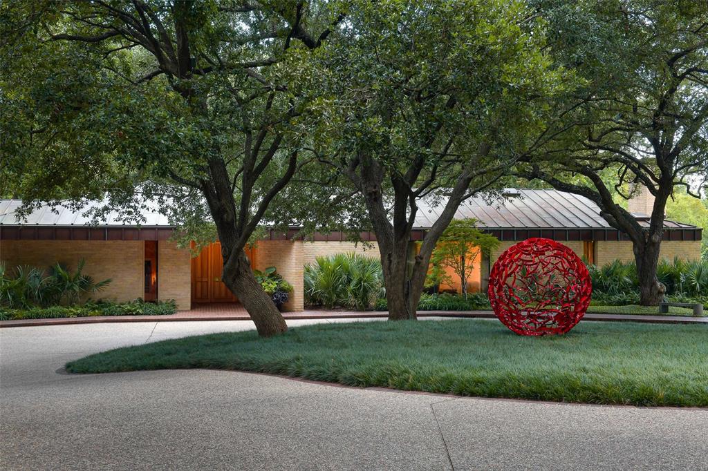 a front view of a house with garden and trees