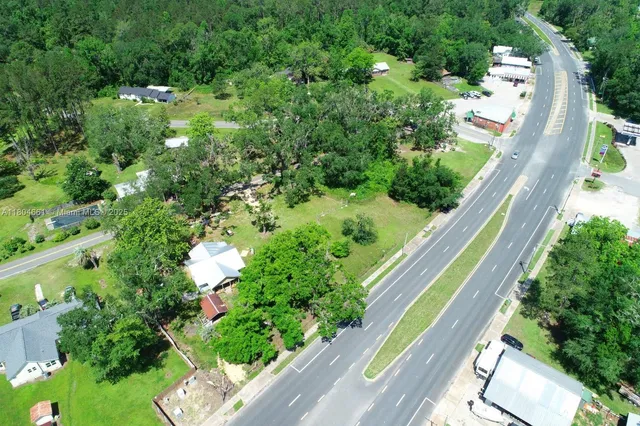 an aerial view of residential house with outdoor space and trees all around