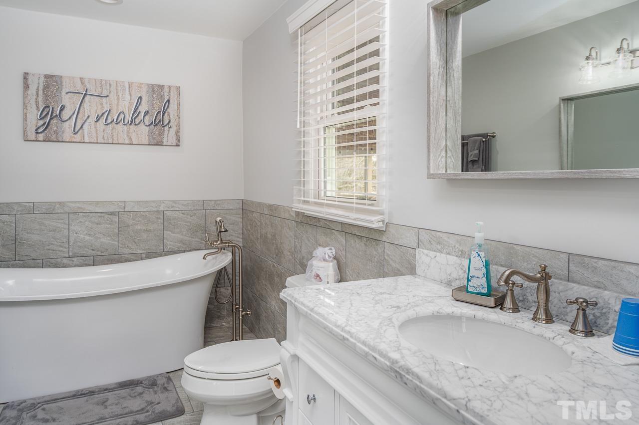 6668 Roby Coe Road Ramseur, NC 27316 - Photo 14 of 59 a bathroom with a granite countertop toilet sink and mirror