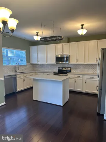 a kitchen with stainless steel appliances a sink cabinets and wooden floor