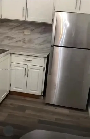 a view of a refrigerator in kitchen and white cabinets