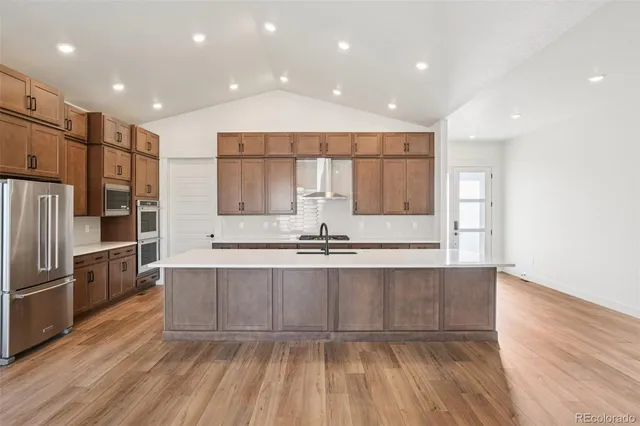 a large kitchen with stainless steel appliances a large counter top a sink and a refrigerator