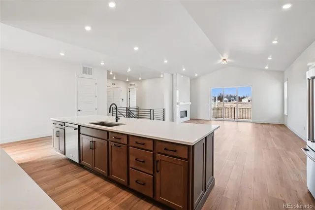 a large kitchen with stainless steel appliances a large counter top a sink and a refrigerator