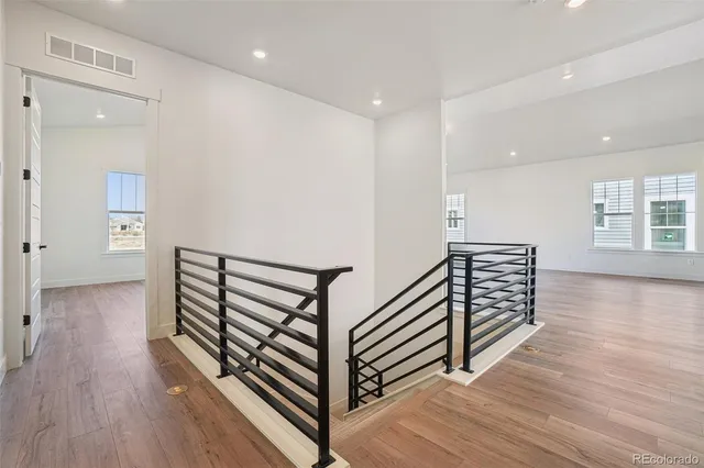 a view of a hallway with wooden floor and stairs