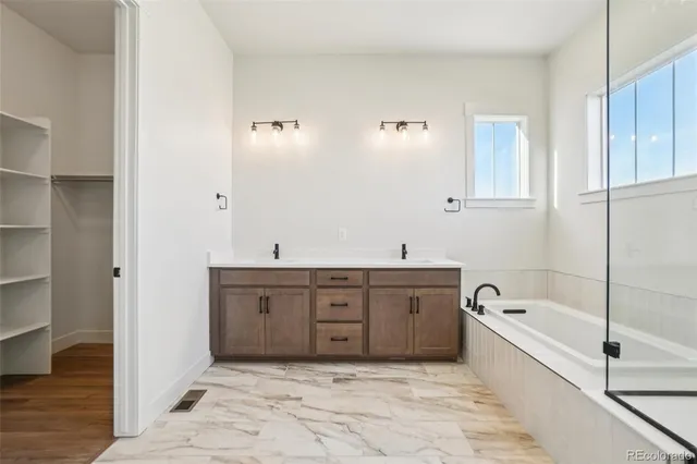 a spacious bathroom with a tub sink and mirror