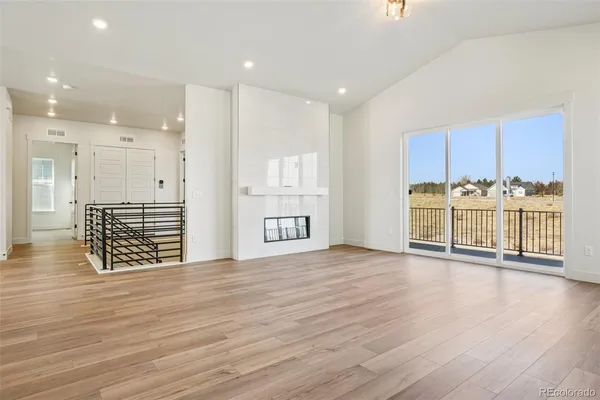 a view of an empty room with wooden floor and windows