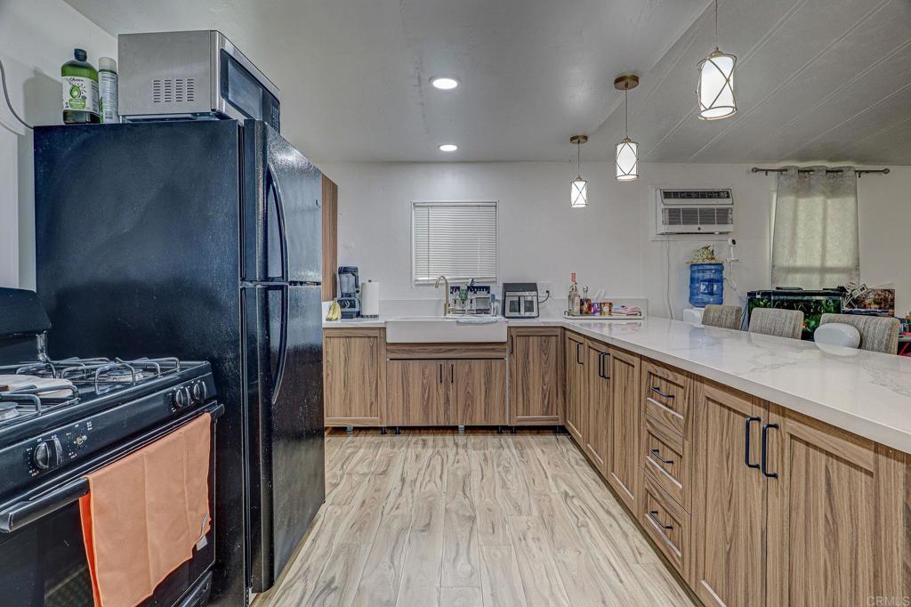 2515 Sweetwater Road, Unit SPC #23 Spring Valley, CA 91977 - Photo 4 of 21 a kitchen with stainless steel appliances a refrigerator a sink dishwasher a stove and white countertops with wooden floor