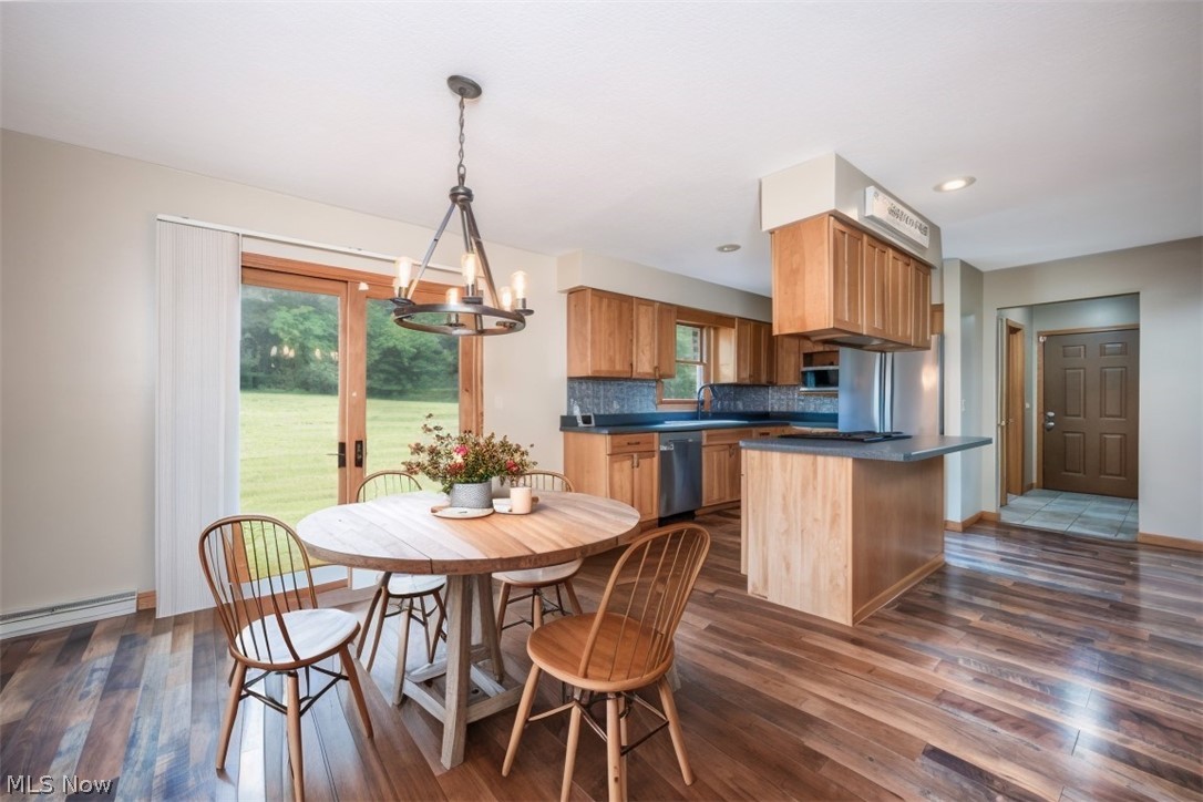 1666 Warner Road Vienna, OH 44473 - Photo 6 of 41 Dining room featuring dark hardwood / wood-style floors, a notable chandelier, sink, and a healthy amount of sunlight