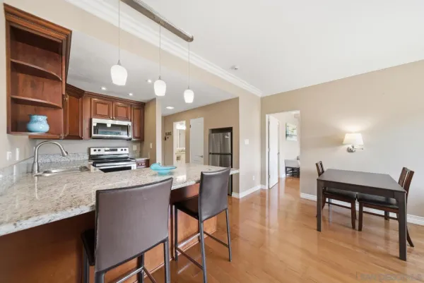 a kitchen with stainless steel appliances granite countertop a stove top oven a sink dishwasher a dining table and chairs with wooden floor