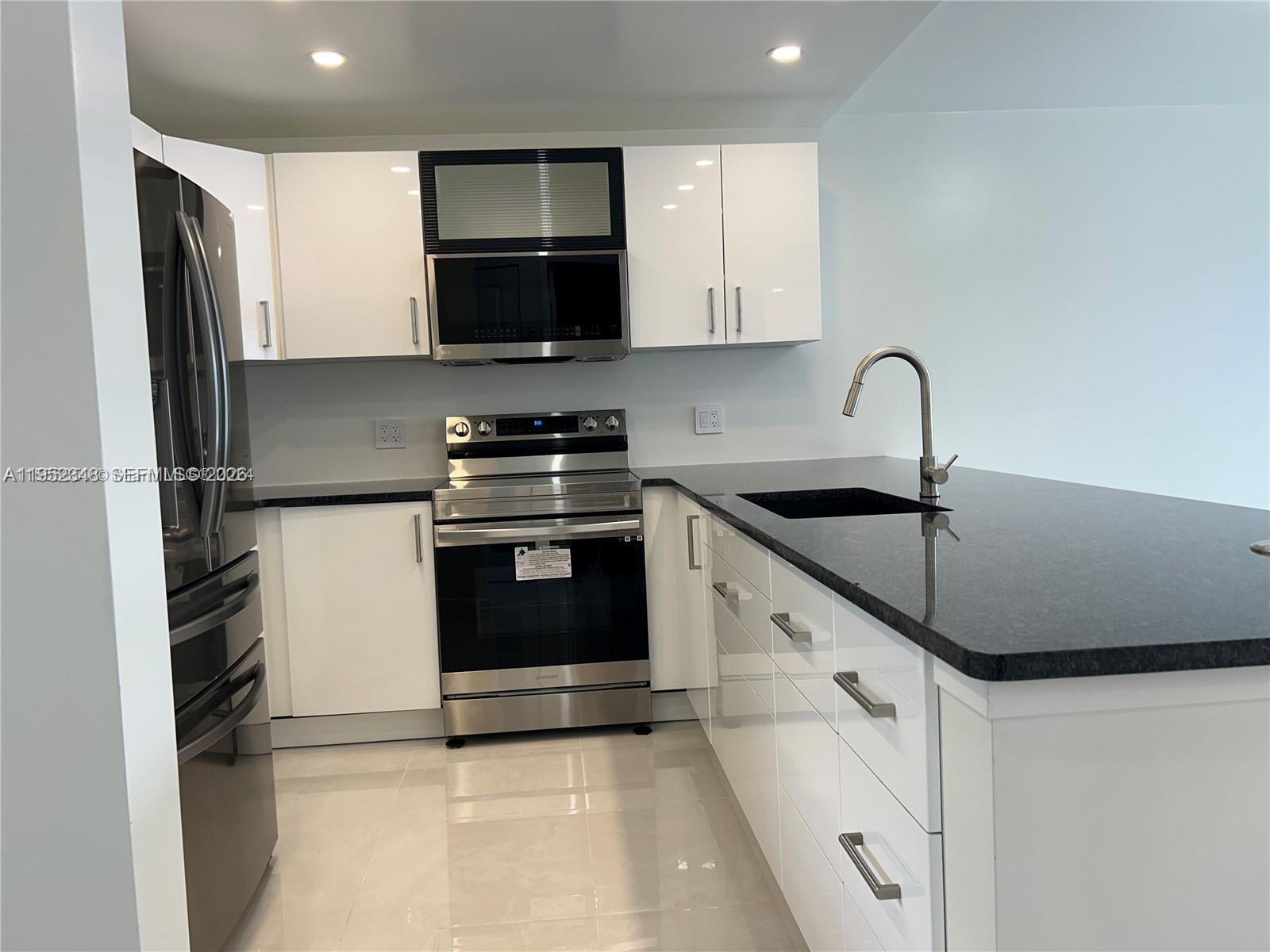 3550 Northeast 169th Street, Unit 304 North Miami Beach, FL 33160 - Photo 13 of 25 a kitchen with stainless steel appliances a sink stove and refrigerator