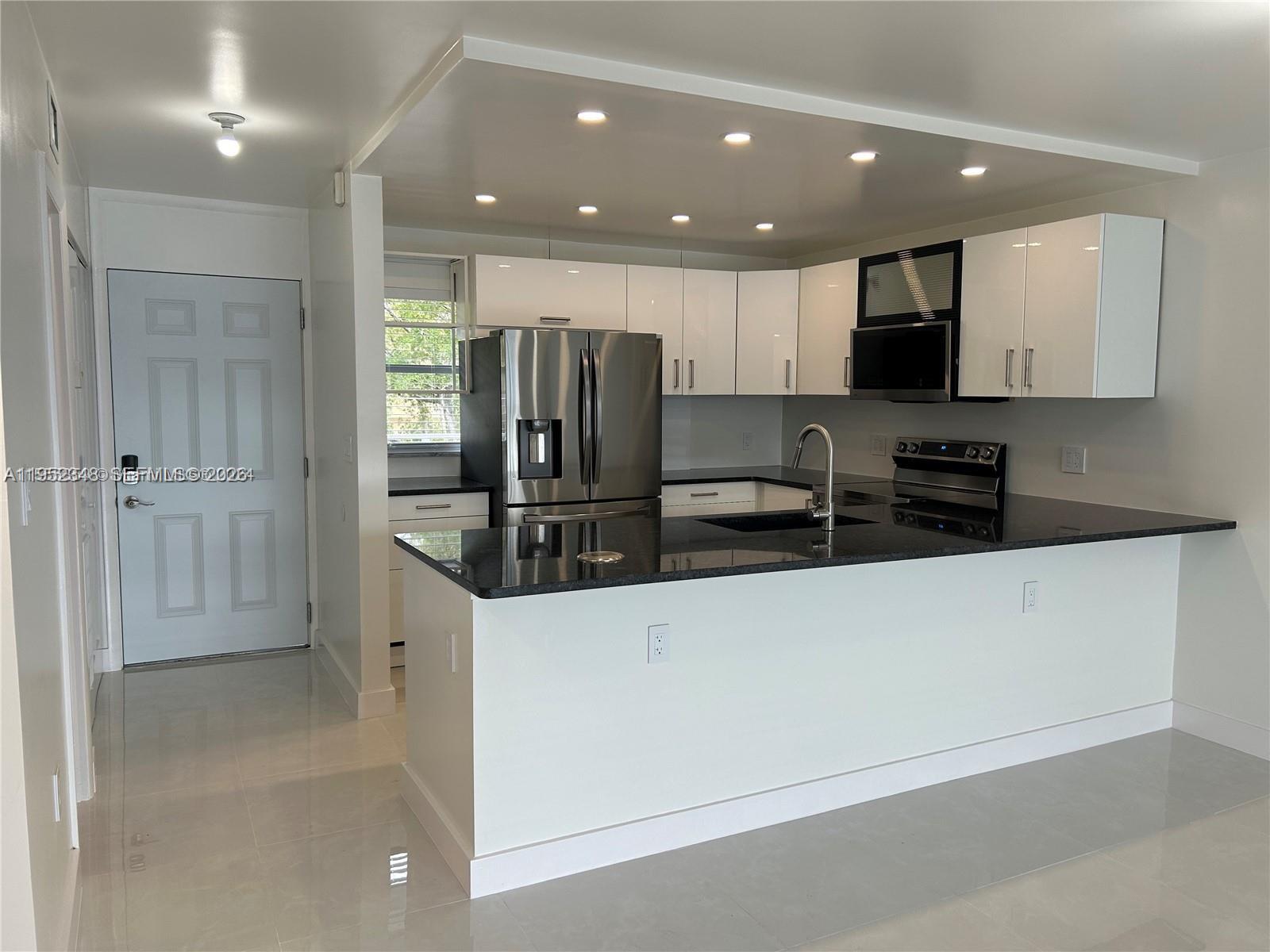 3550 Northeast 169th Street, Unit 304 North Miami Beach, FL 33160 - Photo 14 of 25 a kitchen with stainless steel appliances a refrigerator sink and microwave