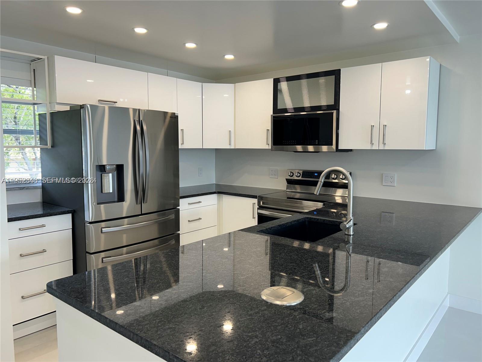 3550 Northeast 169th Street, Unit 304 North Miami Beach, FL 33160 - Photo 3 of 25 a kitchen with a refrigerator a stove a microwave and cabinets