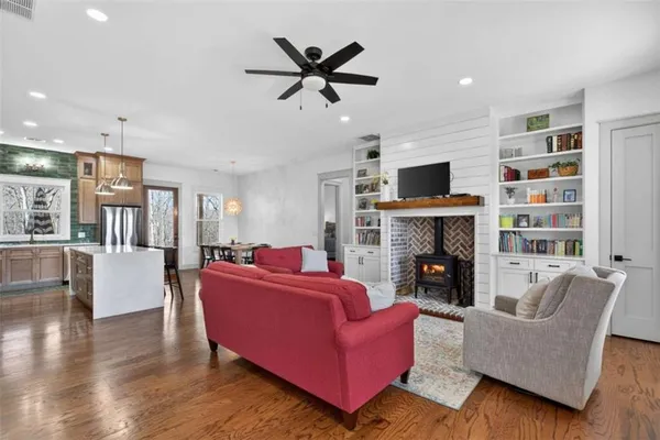 a kitchen with stainless steel appliances granite countertop a refrigerator a sink dishwasher a stove and a dining table with wooden floor