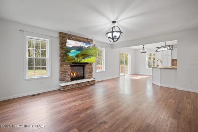 a view of a livingroom with a fireplace wooden floor and windows