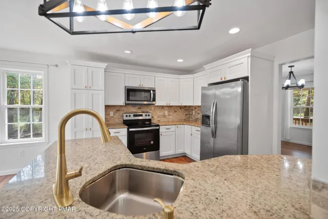 a kitchen with stainless steel appliances granite countertop a sink a refrigerator and a stove top oven