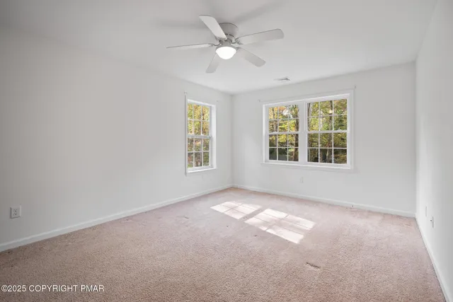an empty room with windows and ceiling fan