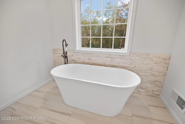 a white bath tub sitting in a bathroom next to a window