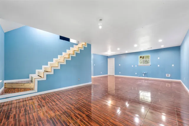 a view of an empty room with stairs and wooden floor