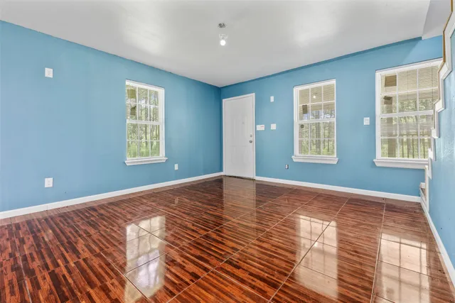 a view of an empty room with a window and wooden floor