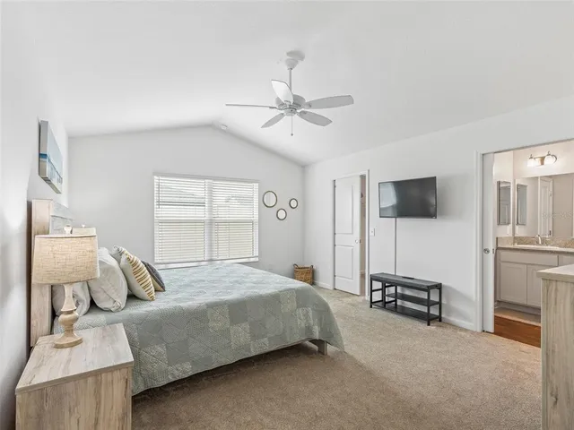 a bedroom with a bed a chandelier and flat screen tv