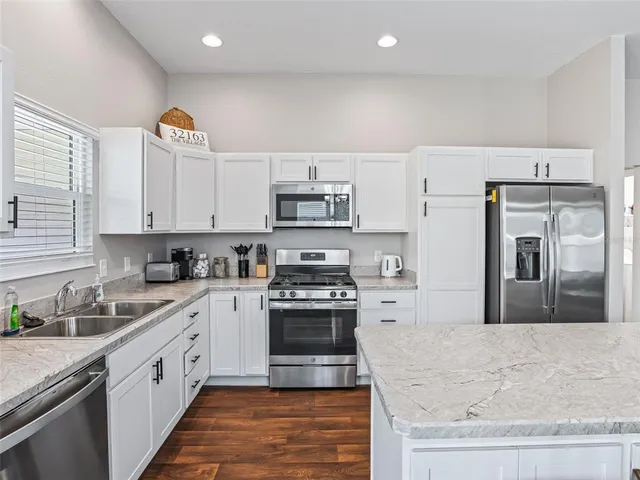 a large kitchen with stainless steel appliances granite countertop a stove a sink and a granite counter tops