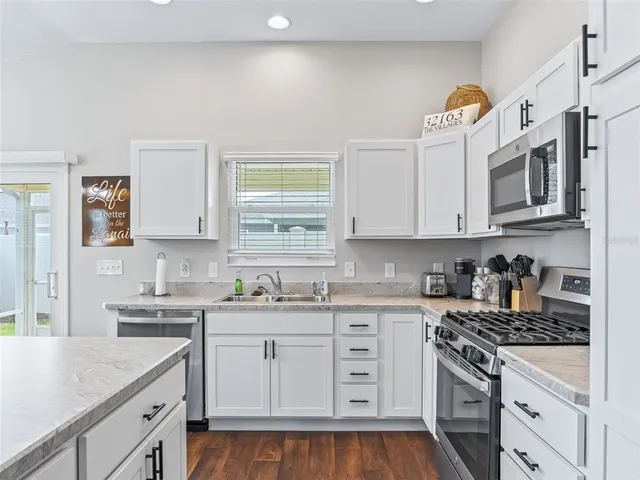 a kitchen with granite countertop a sink a stove a microwave and cabinets