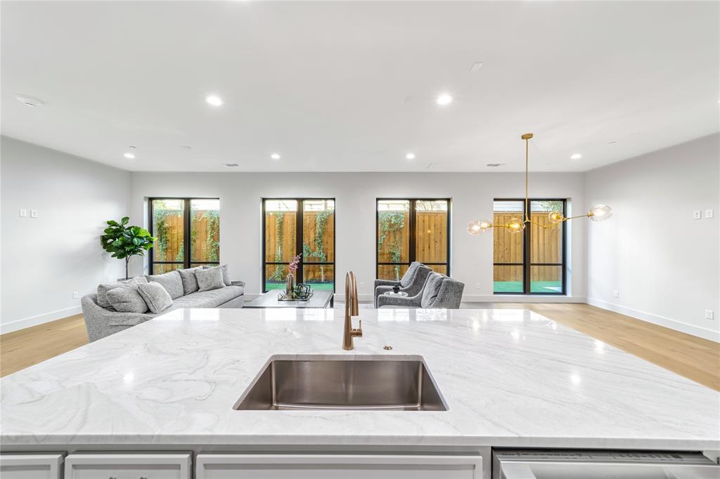 3601 Routh Street, Unit 1B Dallas, TX 75219 - Photo 2 of 22 a kitchen with granite countertop a sink and white cabinets next to a window