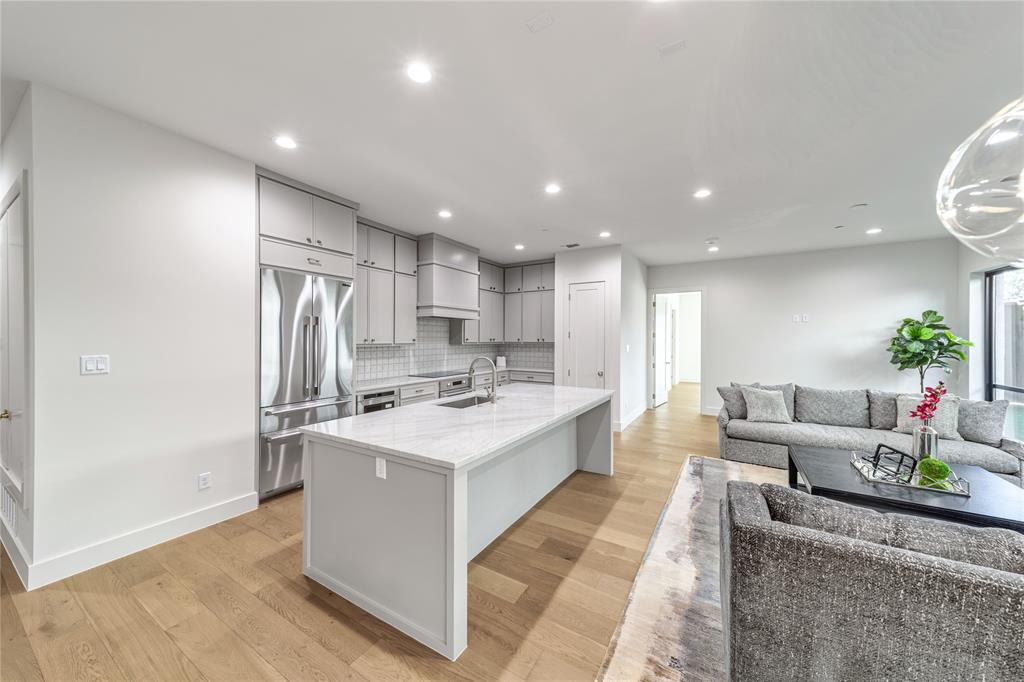 3601 Routh Street, Unit 1B Dallas, TX 75219 - Photo 5 of 22 a large living room with stainless steel appliances kitchen island a table chairs in it and a white cabinets