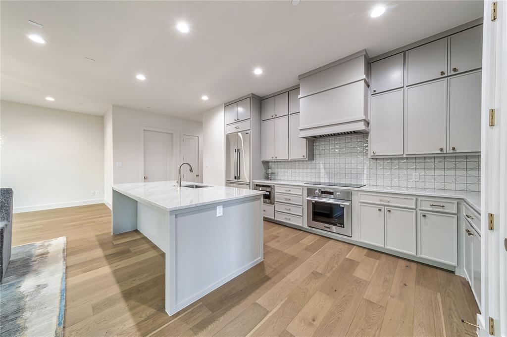 3601 Routh Street, Unit 1B Dallas, TX 75219 - Photo 7 of 22 a large white kitchen with stainless steel appliances granite countertop a sink and cabinets