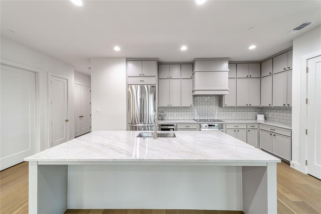 3601 Routh Street, Unit 1B Dallas, TX 75219 - Photo 8 of 22 a kitchen with kitchen island a sink stainless steel appliances and white cabinets