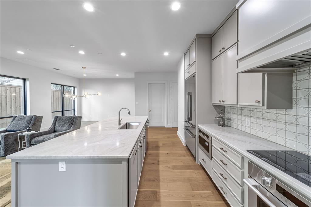 3601 Routh Street, Unit 1B Dallas, TX 75219 - Photo 9 of 22 a large kitchen with kitchen island a sink appliances and a counter top space