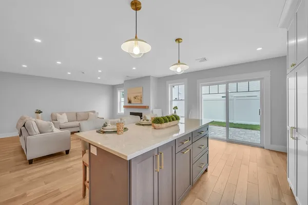 a view of kitchen island a sink and living room with wooden floor