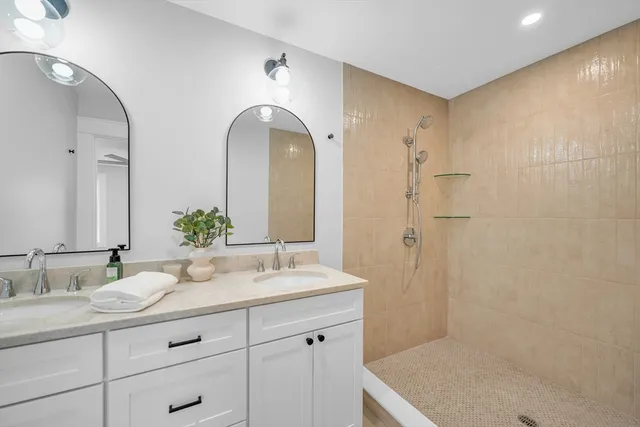 a bathroom with a granite countertop sink a mirror and a shower