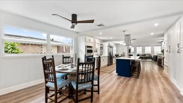 a dining room with stainless steel appliances kitchen island granite countertop a table chairs and a refrigerator
