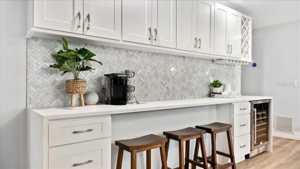 a kitchen with stainless steel appliances a white cabinets and chair