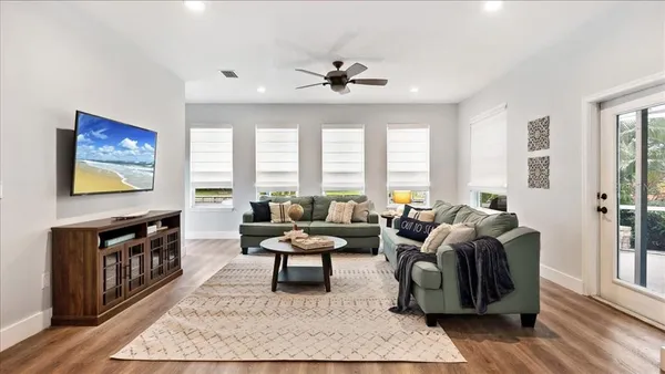 a living room with furniture floor to ceiling window and a flat screen tv